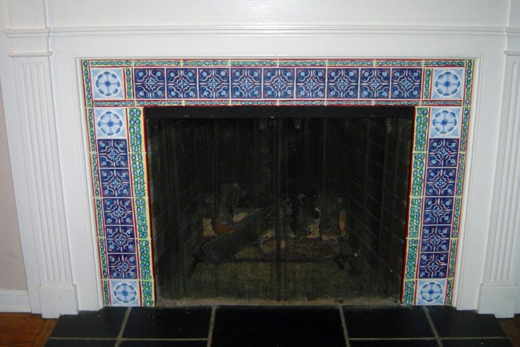 Faux decorative tile painted on slate fireplace surround.