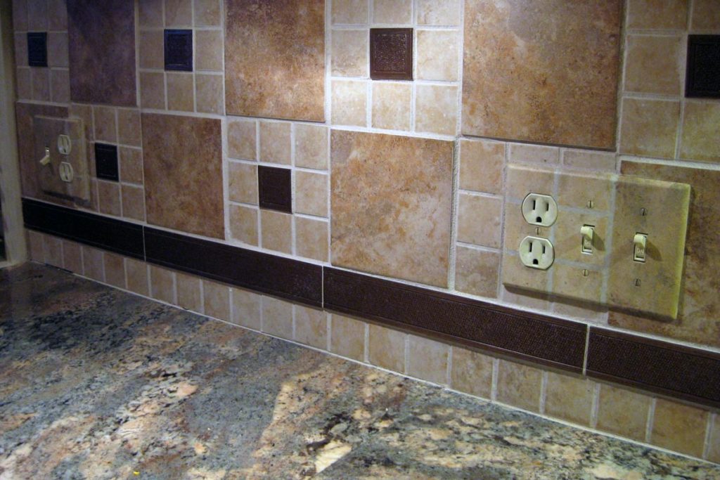Switch/outlet plate painted to blend into backsplash tile pattern.