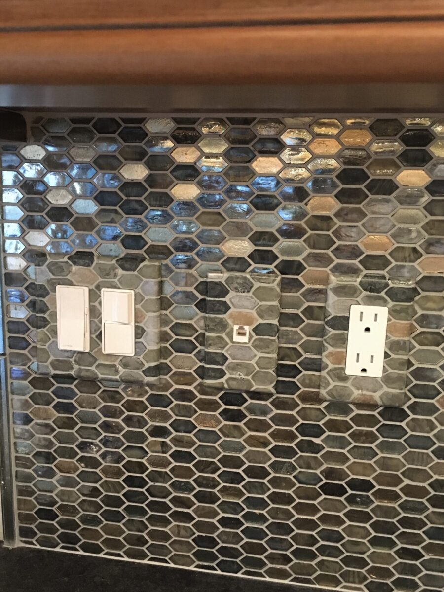 Outlet coverplates painted to match and blend in to glass tile backsplash.
