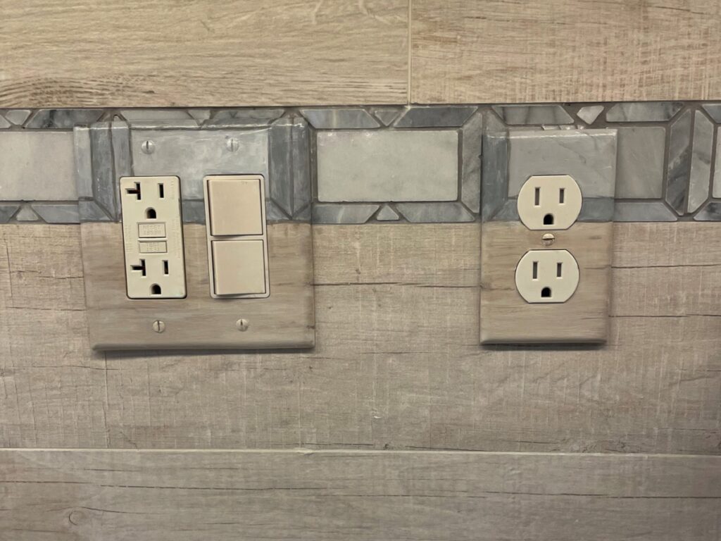 Switch and outlet coverplates painted to blend into the backsplash tile design.