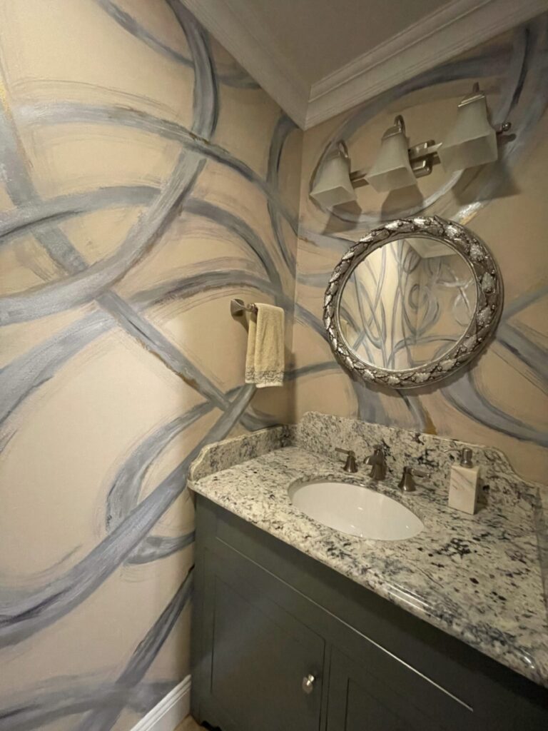 Abstract swirl design painted in powder room. Black, greys, silver and gold on tan background.