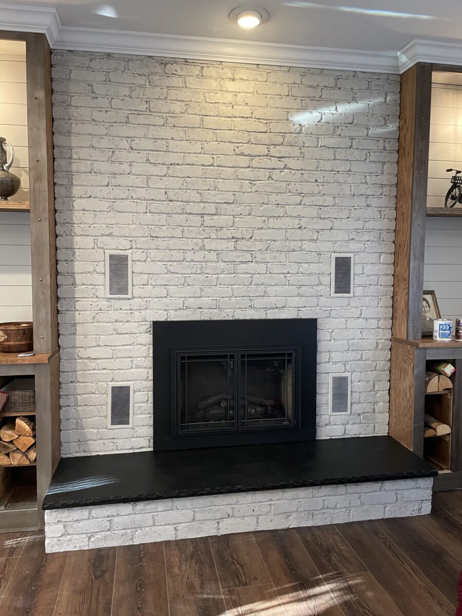Fireplace whitewashed over red bricks and black painted hearth